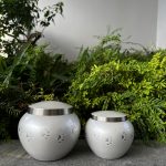 Pearl coloured Pet urn with silver rimmed lid and silver paw prints